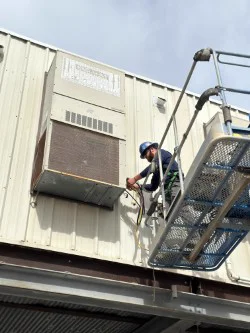 Optimum technician working on a wall-mounted package unit from a lift