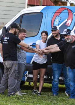The Optimum Air Solutions crew, hands in, in front of a company van